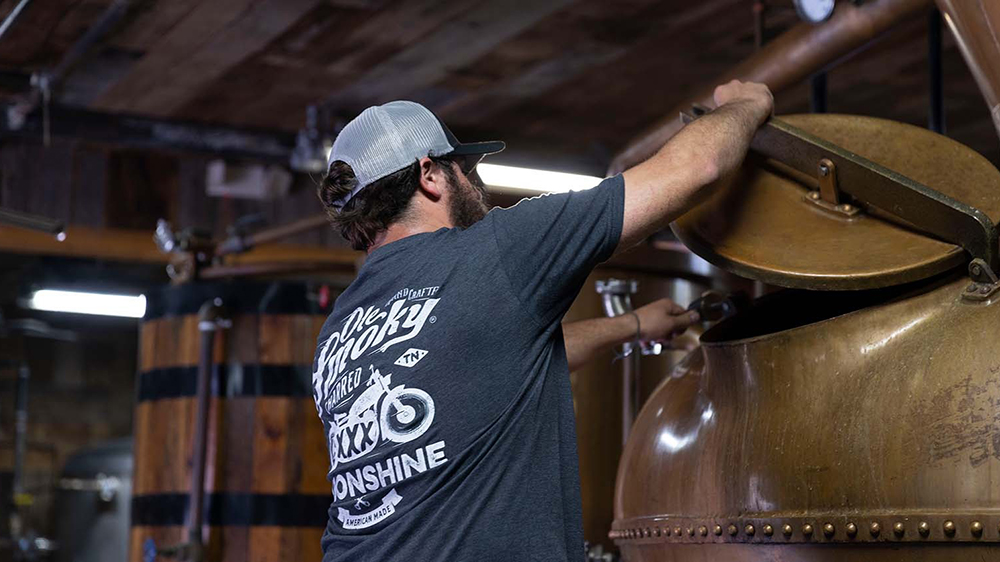 image of a brewery worker checking the still at old smoky moonshine holler