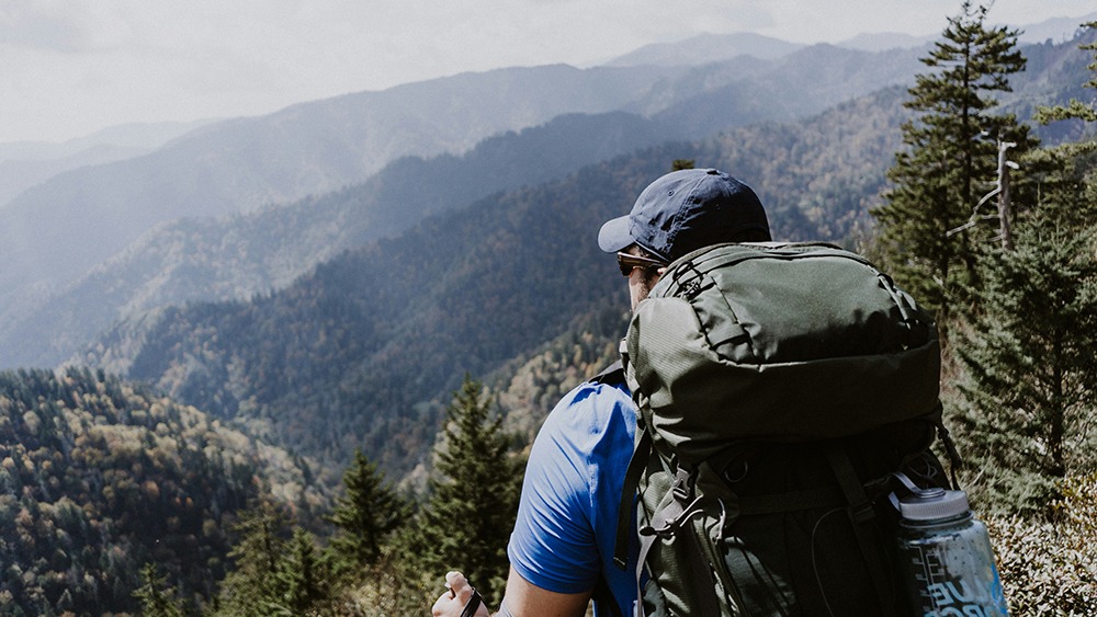 a male hiker looking out over the smoky mountain horizon