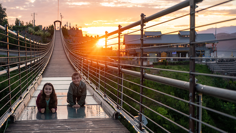 children on the gatlinburg skybridge at sunset looking through the glass floor panels