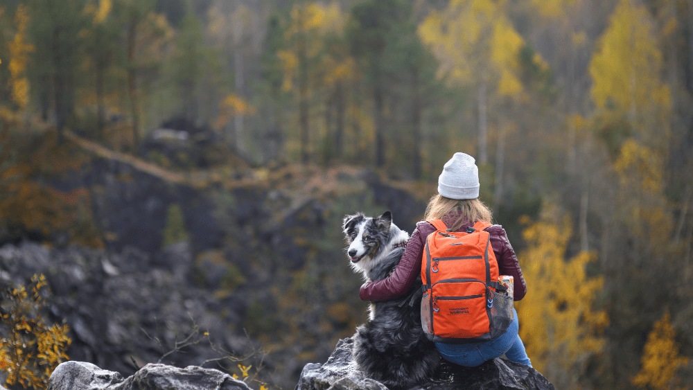 blonde woman with orange backpack hiking with her dog in the great smoky mountains