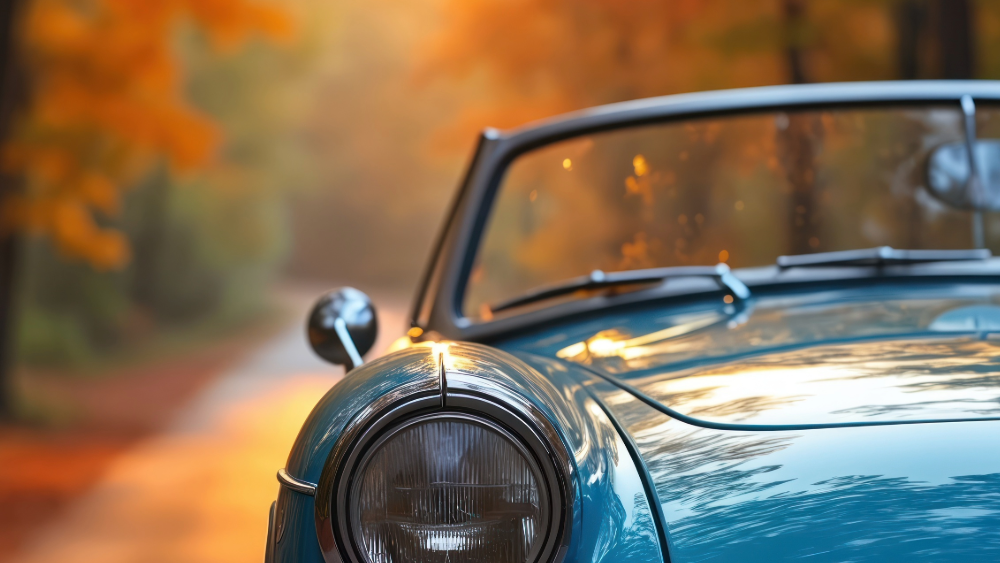 vintage car among fall leaves at sunset