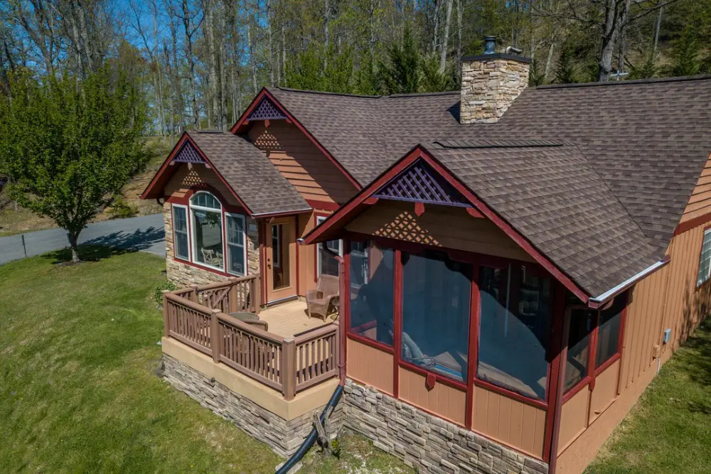 Sunny View Cabin exterior featuring a covered front porch, stone chimney, and wooded setting in Shagbark, Sevierville, TN