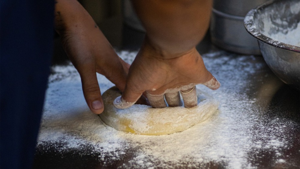 A Pizza Rio chef pressing out fresh dough for pizza.