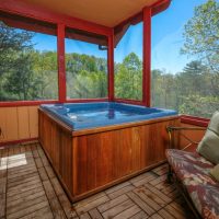 Two-person hot tub on the enclosed deck at Sunny View Cabin in Sevierville TN with Smoky Mountain views through panoramic windows