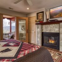 Spacious bedroom at Sunny View Cabin with stone gas fireplace, comfortable seating and warm mountain cabin ambiance